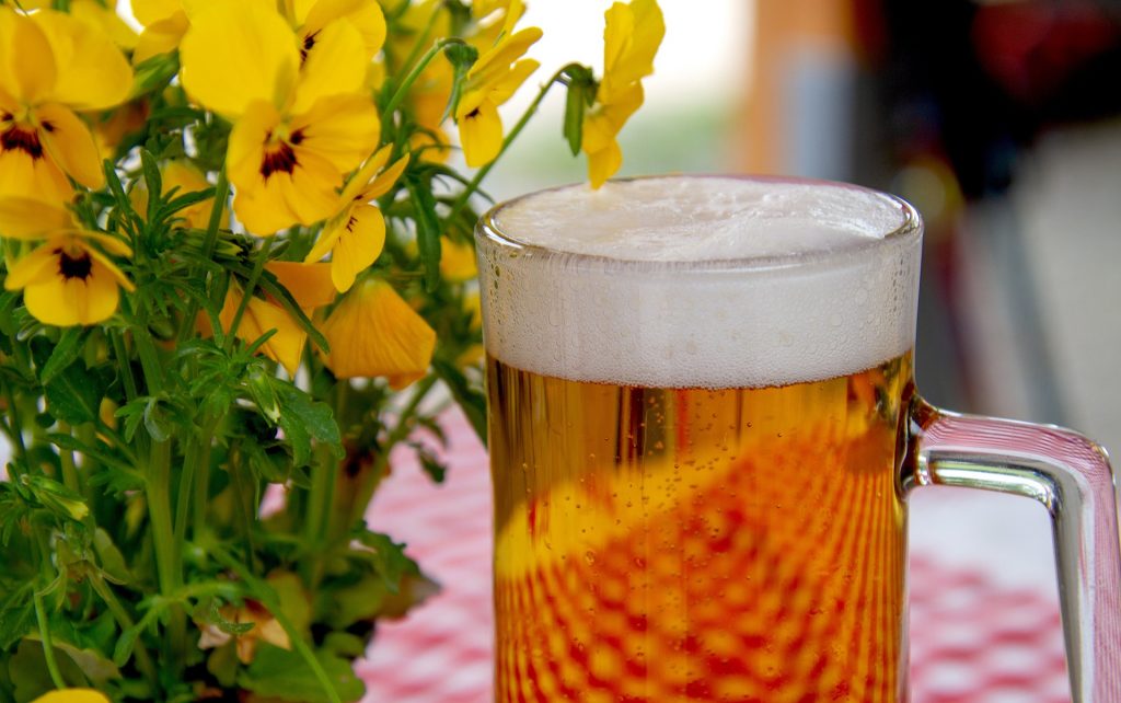 Ein Glas Bier neben Blumen